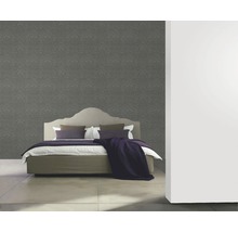 Schlafzimmer mit floral gemusterter Tapete hinter einem Bett