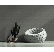 Raumansicht mit gemusterter Tapete, Sessel, Kaktus und Dekofigur