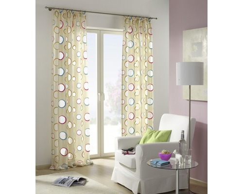 Rideau décoratif à motif de cercles devant une fenêtre dans un salon.