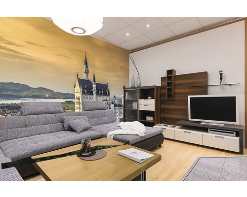 Wohnzimmer mit grauer Eckcouch, Wohnwand und Fototapete mit Schlossmotiv