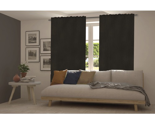 Wohnzimmer mit Sofa und blickdichten, schwarzen Gardinen vor dem Fenster.