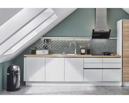 Cuisine avec armoires blanches, évier, hotte aspirante et poubelle sous un vasistas