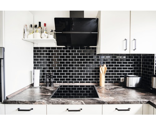 Moderne Küche mit schwarzen Fliesen, Dunstabzugshaube und Kochfeld