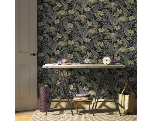 Büroraum mit gemusterter Tapete mit Flamingos und tropischen Blättern, einem Holztisch auf Böcken und dekorativen Elementen.