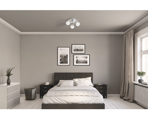 Chambre avec lit, tables de chevet, commode, plafonnier et décorations murales
