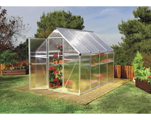 Gewächshaus mit geöffneter Tür, Pflanzenregalen und Pflanzen auf einem Rasen