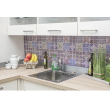 Évier de cuisine avec robinet et plan de travail devant un mur de carreaux à motifs