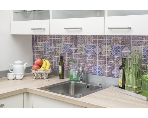 Évier de cuisine avec robinet et plan de travail devant un mur de carreaux à motifs