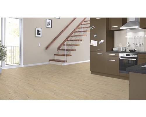 Pièce lumineuse avec sol stratifié, escalier et kitchenette.