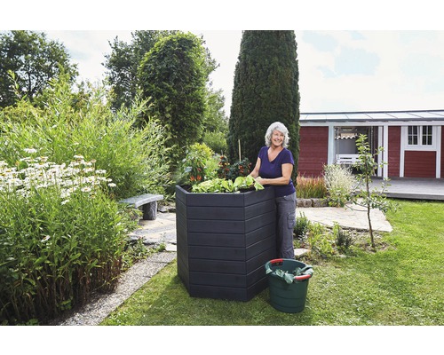 Femme jardine près d''un potager surélevé dans le jardin.