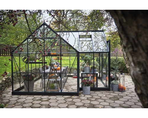 Gewächshaus mit Pflanzen und Möbeln im Garten