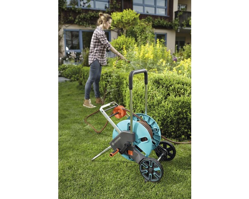 Frau benutzt Gardena Gartenschlauchwagen im Garten