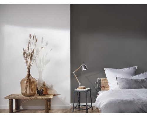 Dekoratives Schlafzimmer mit Bett, Lampe und Vasen auf einem Holztisch