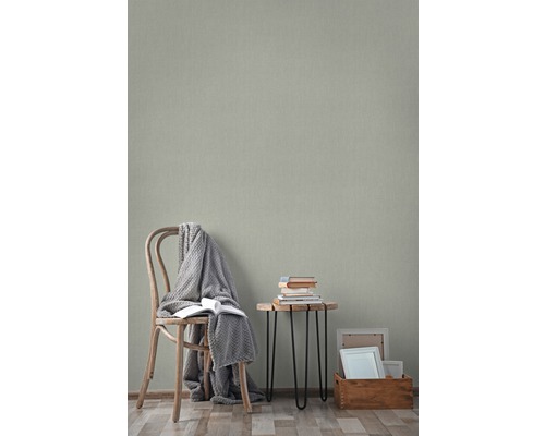 Wohnraum mit Holzstuhl, Beistelltisch mit Büchern und gemusterter Tapete