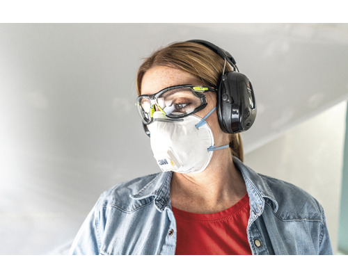 Frau mit Schutzbrille, Atemschutzmaske und Kapselgehörschutz