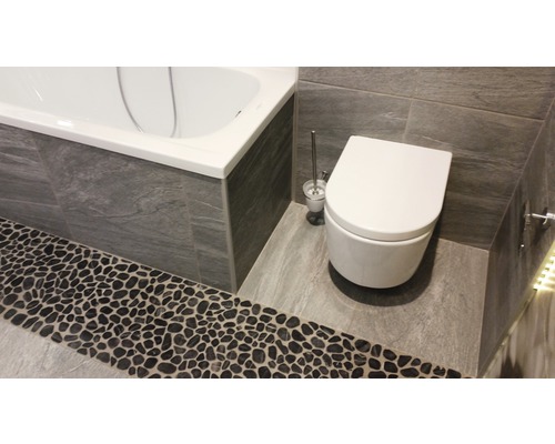 Badezimmer mit Badewanne, Toilette und Steinboden