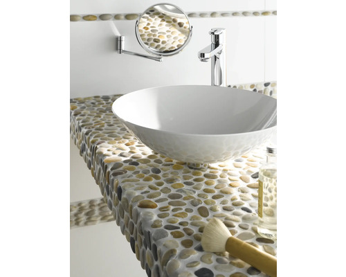 Badezimmer-Szene mit Aufsatzwaschbecken, Armatur, Wandspiegel und einer Ablage mit Kieselsteinen