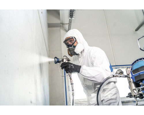Person mit Schutzanzug und Atemschutzmaske beim Sprühen mit einer Farbspritzpistole