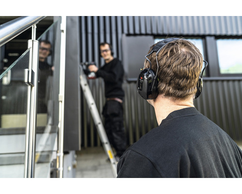 Homme portant une protection auditive lors de travaux de montage à l''extérieur.