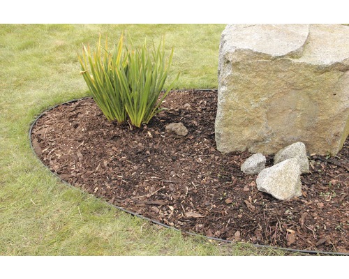 Garten mit Rasenfläche, Pflanzen und einem großen Stein, umrandet von einer Rasenkante