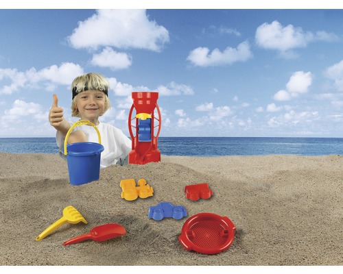 Junge mit Sandspielzeug am Strand, inklusive Eimer, Schaufel, Rechen, Sieb und Sandmühle
