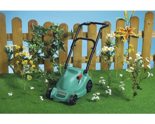 Tondeuse Bosch sur pelouse devant une clôture en bois et des fleurs