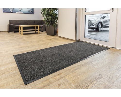 Tapis de sol gris devant une porte d''entrée dans une pièce lumineuse.