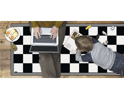 Spielteppich mit Schachbrettmuster, darauf eine Person mit einem Laptop, ein Kind, Spielzeugautos, ein Buch, belegte Brote und ein Getränk