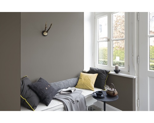 Coin salon confortable avec coussins, couverture, table et fenêtre pour un intérieur relaxant