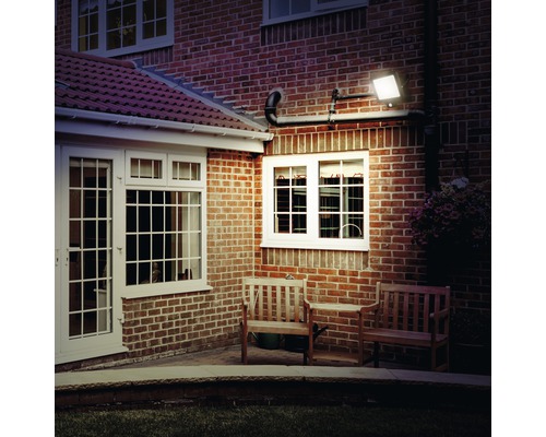 Außenbereich eines Hauses mit Fassade aus Ziegelsteinen und montiertem LED-Strahler.