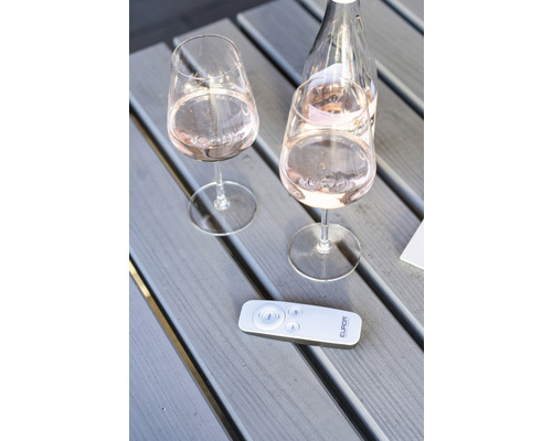 Zwei Weingläser und eine Flasche Wein mit einer Fernbedienung auf einem Holztisch