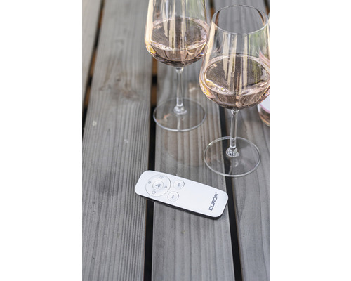 Deux verres à vin remplis et une télécommande sur une table en bois