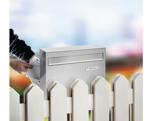 Briefkasten aus Edelstahl mit Sichtfenster und Namensschild an einem Gartenzaun