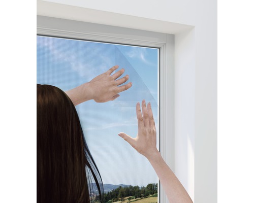 Une femme installe une moustiquaire sur une fenêtre