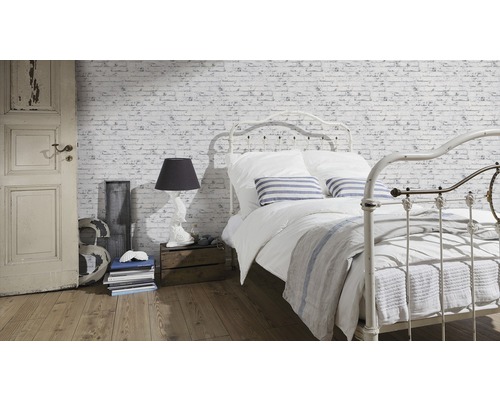 Chambre claire avec lit devant un papier peint en briques