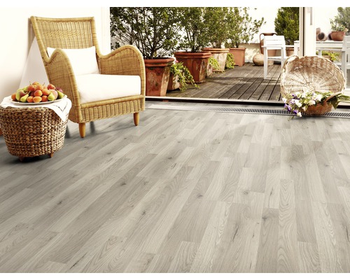 Pièce claire avec sol stratifié, fauteuil en rotin et plantes en pot sur le balcon