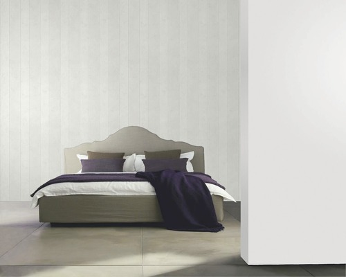 Schlafzimmer mit Bett, Kissen und Decke vor einer gestreiften Wand