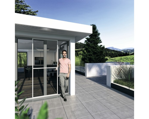 Homme entrant dans une maison avec porte coulissante et terrasse carrelée.