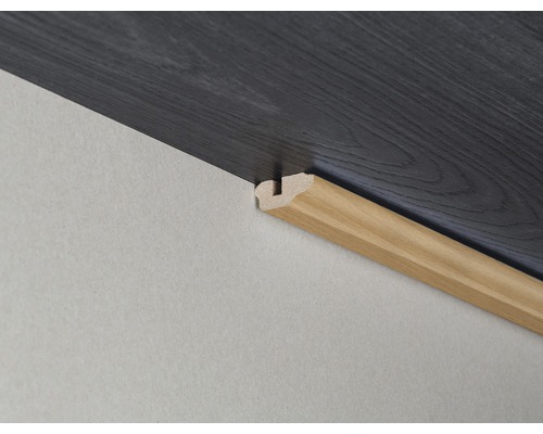 Gros plan d''une plinthe en bois sur un mur avec un sol stratifié