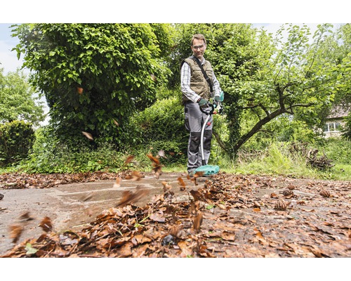 Ein Mann benutzt einen Akku-Laubbesen zur Gartenarbeit, um Laub zu entfernen.