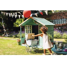 Enfant jouant avec une poussette devant une cabane de jeu dans le jardin.