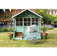 Scène avec une cabane pour enfants, une poussette et une décoration de jardin sur une pelouse