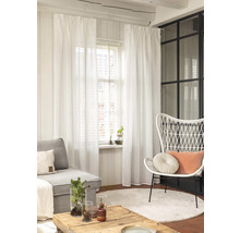 Salon avec canapé, fauteuil, table, tapis et rideaux blancs.