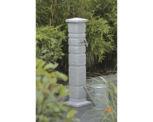 Point d''eau de jardin en pierre avec robinet et arrosoir dans le jardin