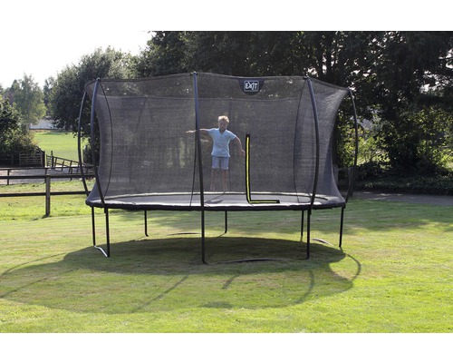 Outdoor Trampolin mit Sicherheitsnetz und springendem Kind im Garten