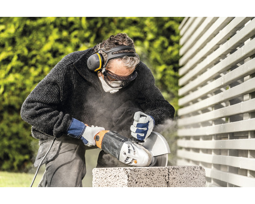 Un homme coupe de la pierre avec une meuleuse d''angle et des vêtements de protection