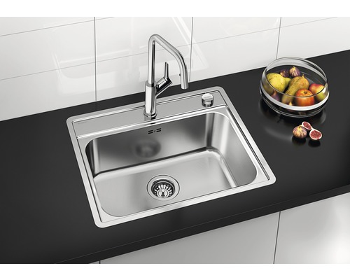 Évier en acier inoxydable avec robinet sur un plan de travail avec un panier de fruits