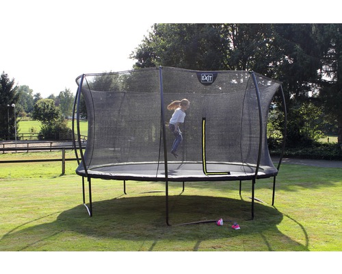 Trampolin mit Sicherheitsnetz im Garten, ein Kind springt