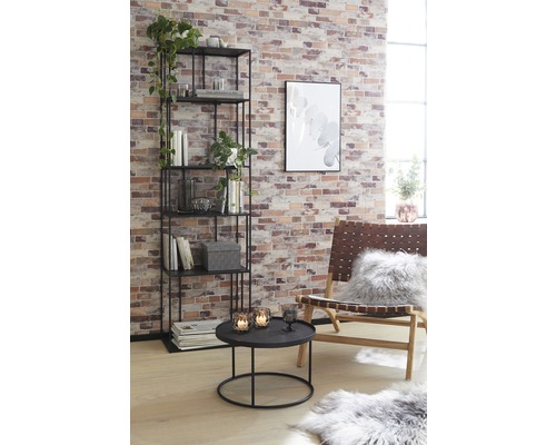 Salon avec étagère, table et fauteuil devant un mur de briques