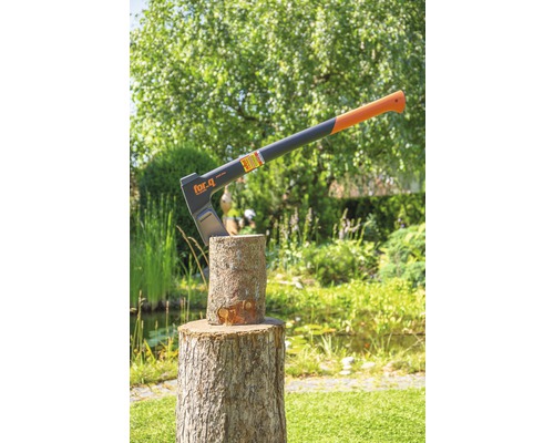 For.q Logo. Eine Axt steckt in einem Holzscheit im Garten.